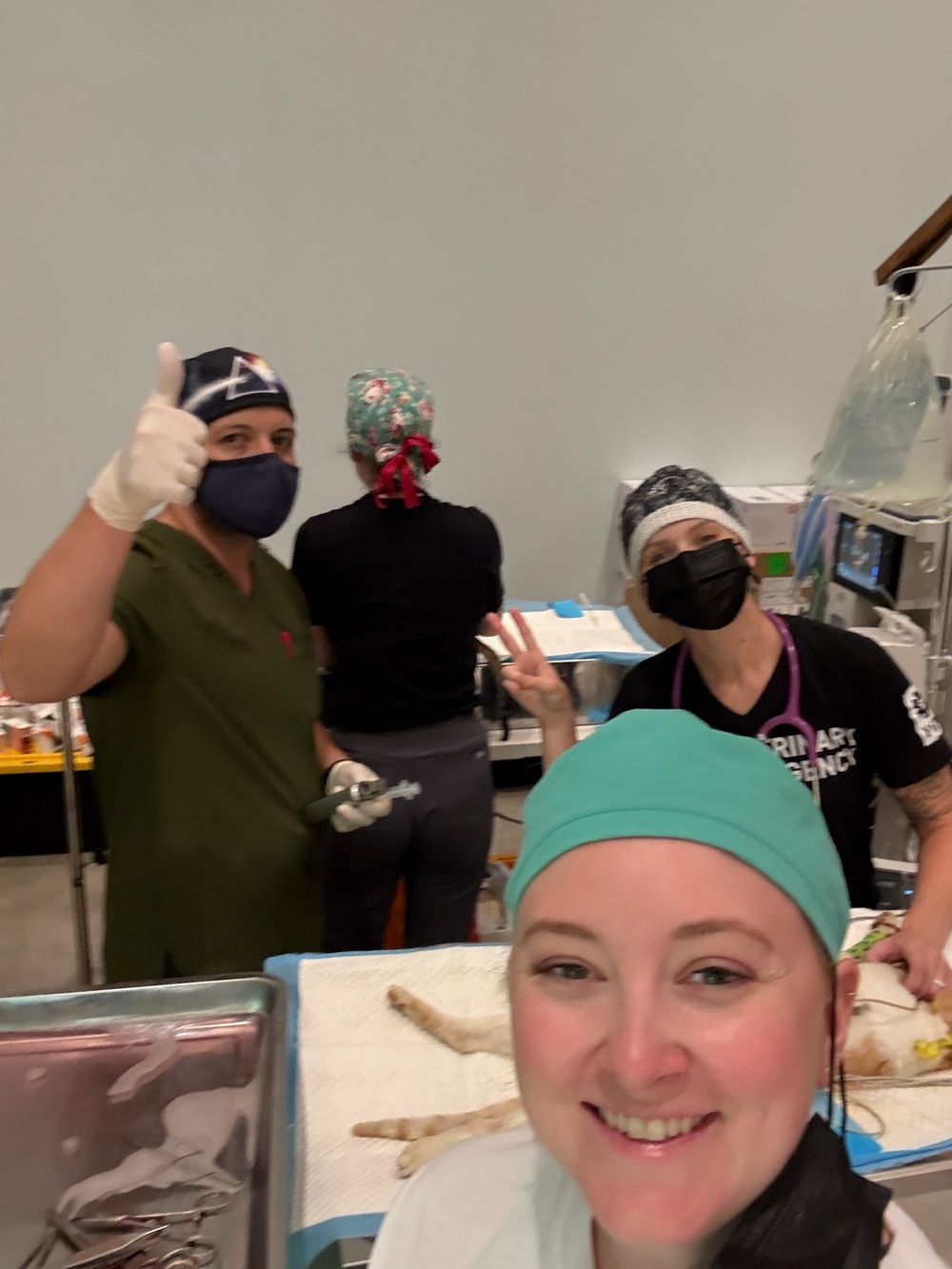 Four PRCP surgical team members take a selfie in the operating room, two giving thumbs up and peace signs