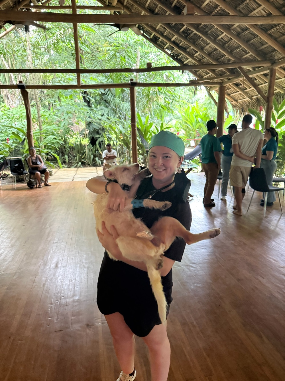 A PRCP volunteer laughs as a happy golden dog licks her face inside the clinic pavilion