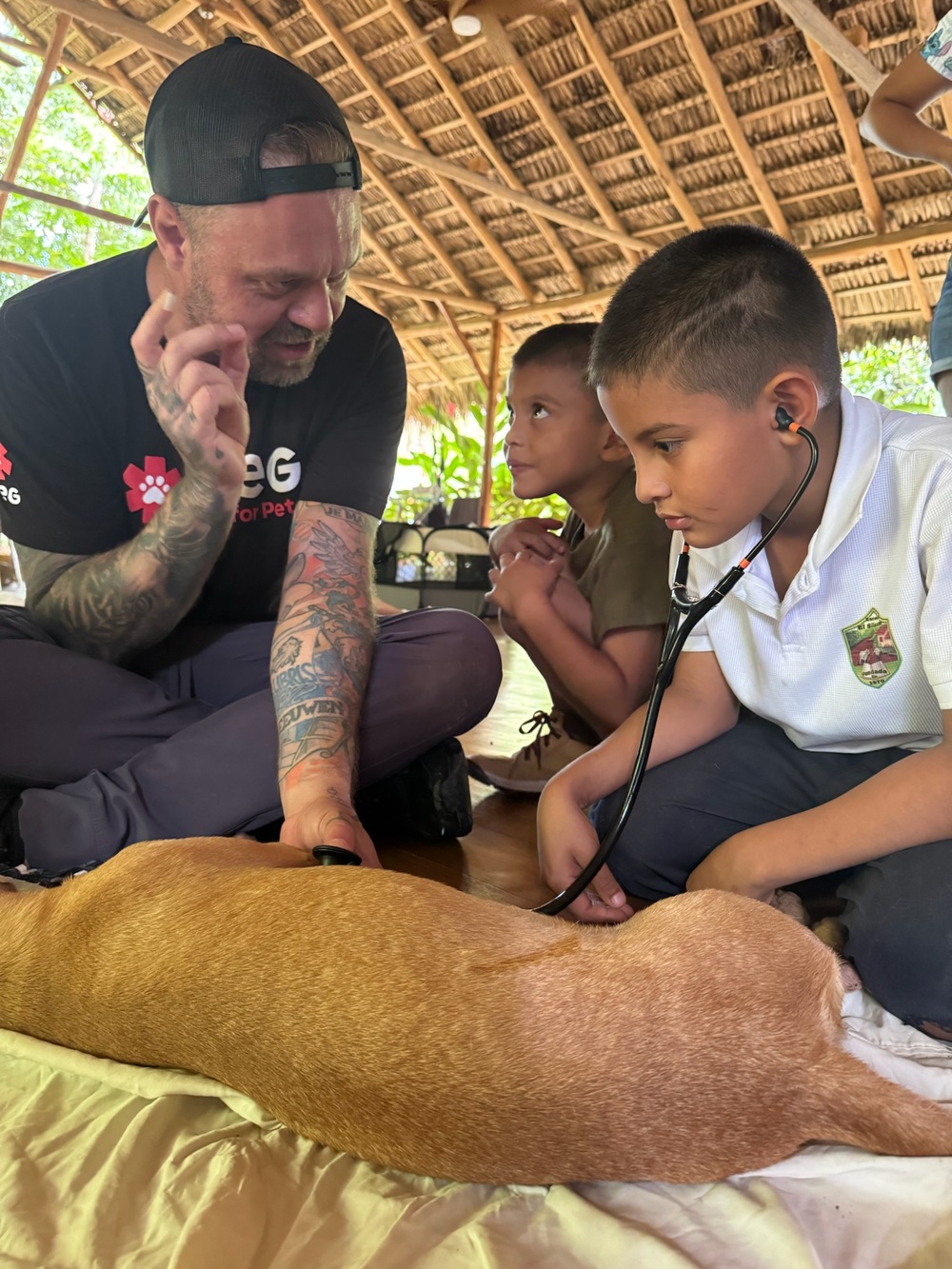 A PRCP volunteer guides two local Costa Rican boys as they listen to a dog's heartbeat with a stethoscope